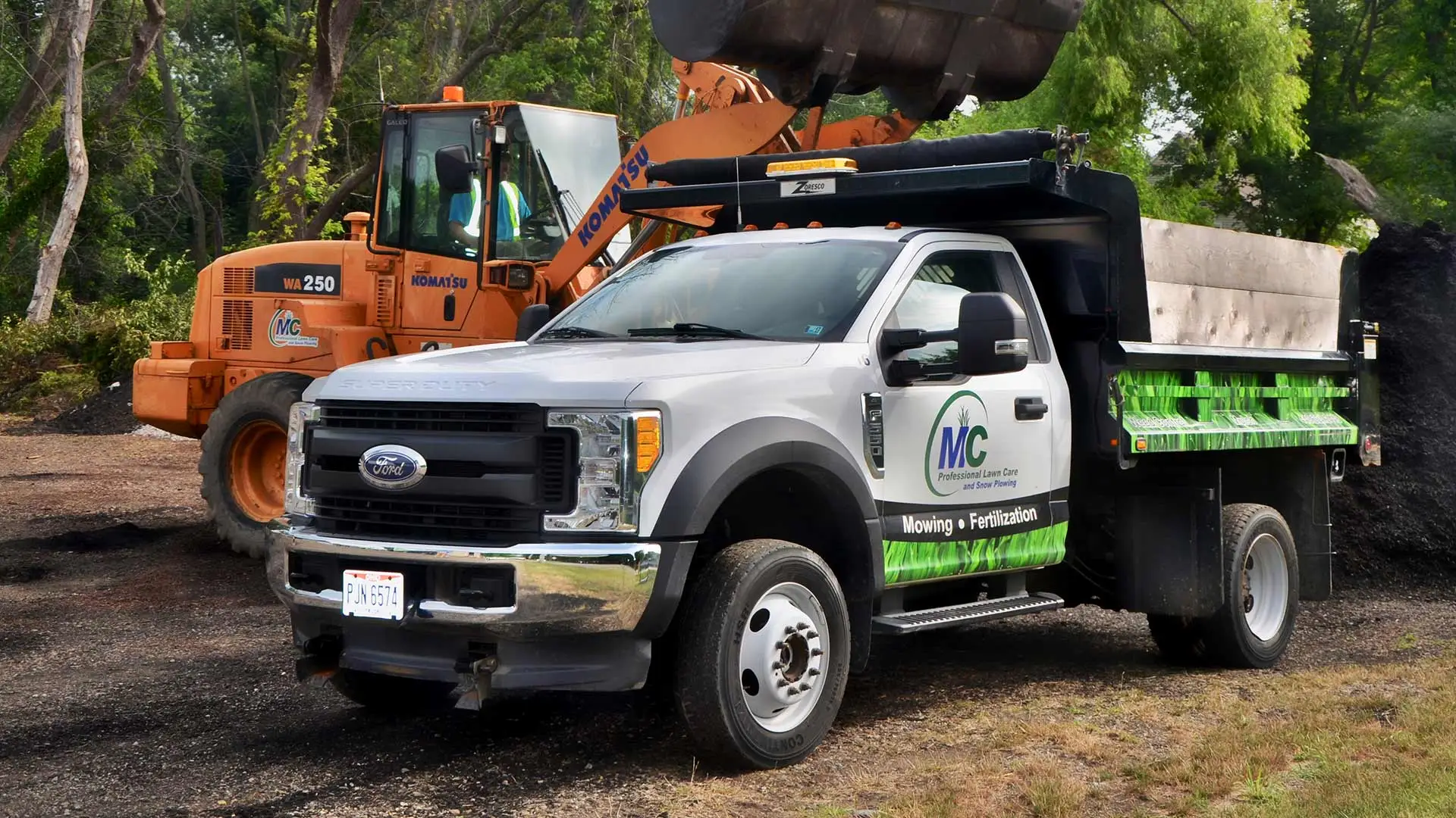 MC Professional Lawn Care and Snow Plowing truck being loaded with mulch by large machine in Madison, OH.