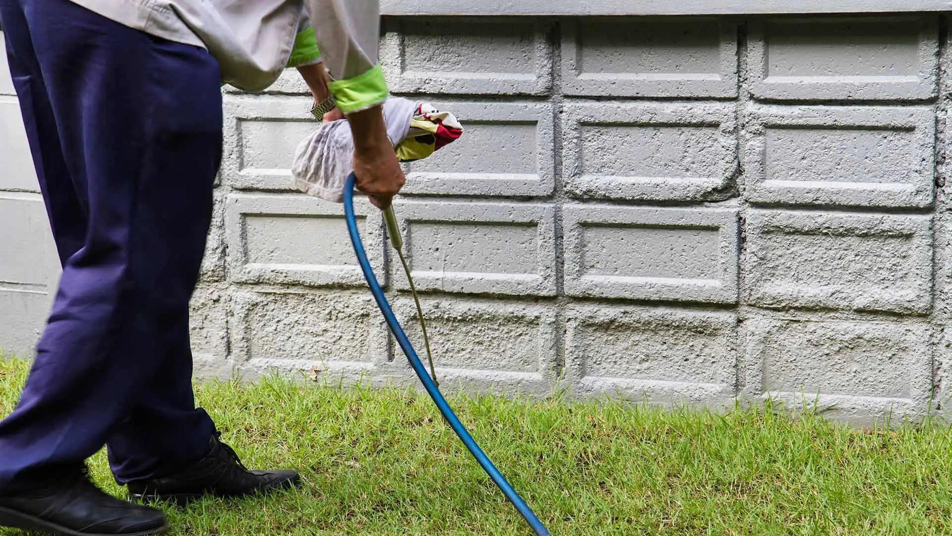 Perimeter pest control specialist applying a solution around a home near Painesville, OH.