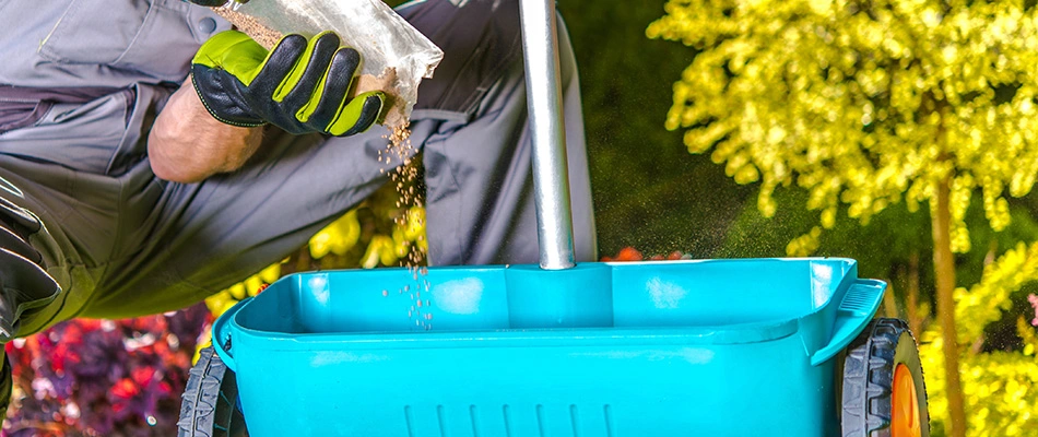 Lawn fertilizer dispenser begin filled by a professional with granular fertilizer near Madison, OH.