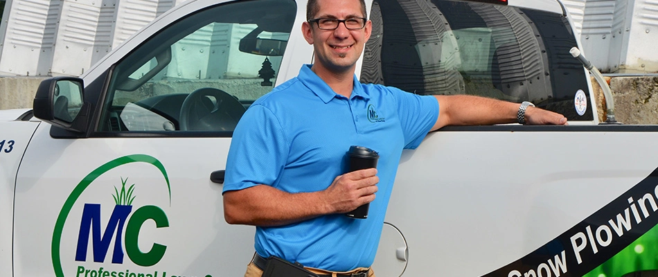 MC Professional Lawn Care and Snow Plowing owner standing with a large coffee with a company truck near Madison, OH.