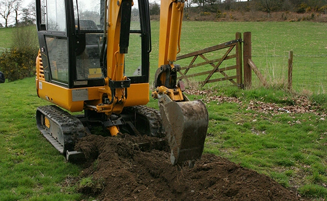 Mini excavator digging a drainage hole in Madison, OH.