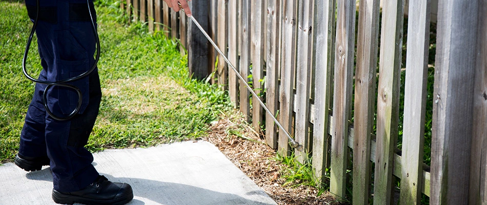 Professional spraying the perimeter of a property with pest control in Painesville, OH.